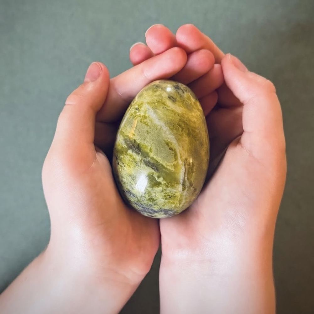 Polished green Connemara marble stone held in two hands showing natural green patterns